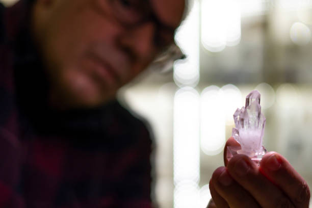 Man examining small, raw amethyst crystals closely, appreciating their unique formation.