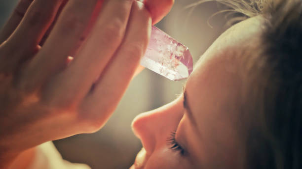 Person places amethyst crystals on their forehead, engaging in spiritual healing.