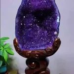 Museum-quality 53 lb natural amethyst cave known as the Imperial Grotto, featuring deep purple crystals resting on a tall elevated carved wood pedestal