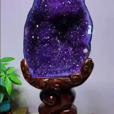 Museum-quality 53 lb natural amethyst cave known as the Imperial Grotto, featuring deep purple crystals resting on a tall elevated carved wood pedestal