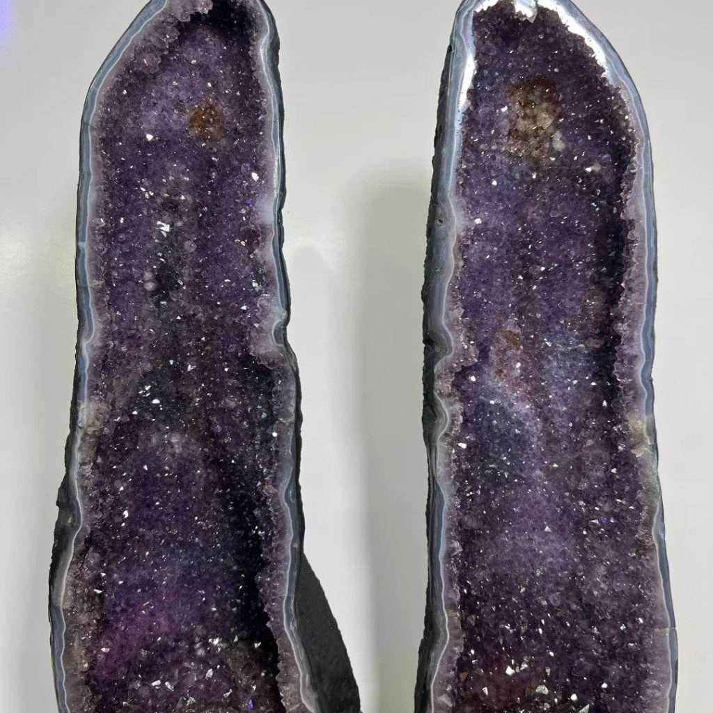 Museum-quality 121 lb matching Uruguayan amethyst twin towers known as the Twin Guardian Towers, featuring deep velvet purple crystals on custom carved wood stands