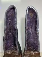 Museum-quality 121 lb matching Uruguayan amethyst twin towers known as the Twin Guardian Towers, featuring deep velvet purple crystals on custom carved wood stands