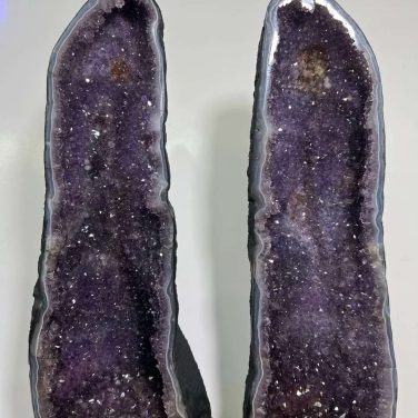 Museum-quality 121 lb matching Uruguayan amethyst twin towers known as the Twin Guardian Towers, featuring deep velvet purple crystals on custom carved wood stands