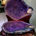 Monumental 41.36 lb amethyst treasure basin known as the Prosperity Clamshell Pair, featuring a top and bottom display with deep purple crystals, a white calcite inclusion, and a stand carved with coin motifs.