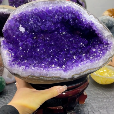 Museum-quality 11 lb amethyst treasure basin known as the Crystal Cavern Bowl, featuring a wide mouth and deep royal purple crystals on a custom wood stand