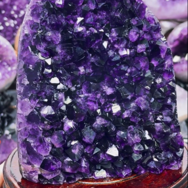Museum-quality AAA Uruguayan amethyst geode named The Velvet Peak, featuring densely packed deep grape-jelly purple crystals on a wood stand, specimen
