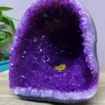 Museum-quality 13.2 lb natural amethyst cave known as the Deep Void Sanctuary, featuring a deep dark purple cavity and bright white agate rim on a wood stand