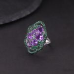 Low-light studio shot of the Heirloom Amethyst Ring, highlighting the internal fire of the purple gems and the heavy Baroque silver relief.