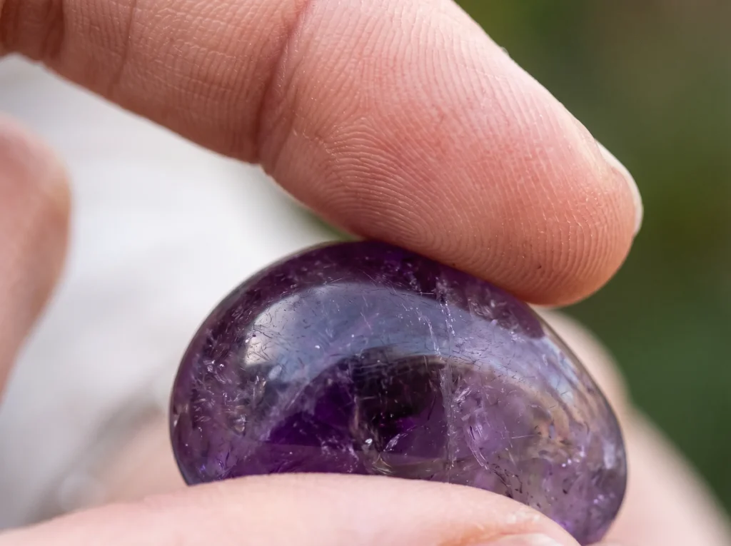amethyst anxiety relief — close-up of a hand holding a smooth tumbled stone for tactile grounding