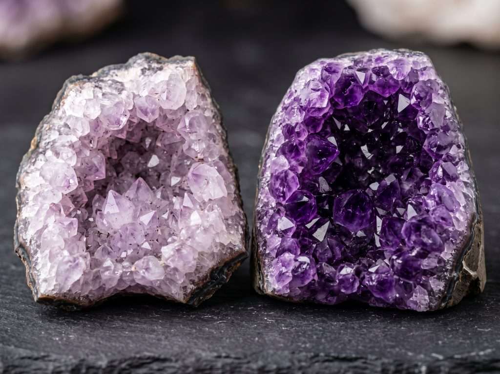 Close-up color comparison showing a pale lavender Brazilian amethyst cave next to a deep purple Uruguayan geode, illustrating differences in natural color saturation.